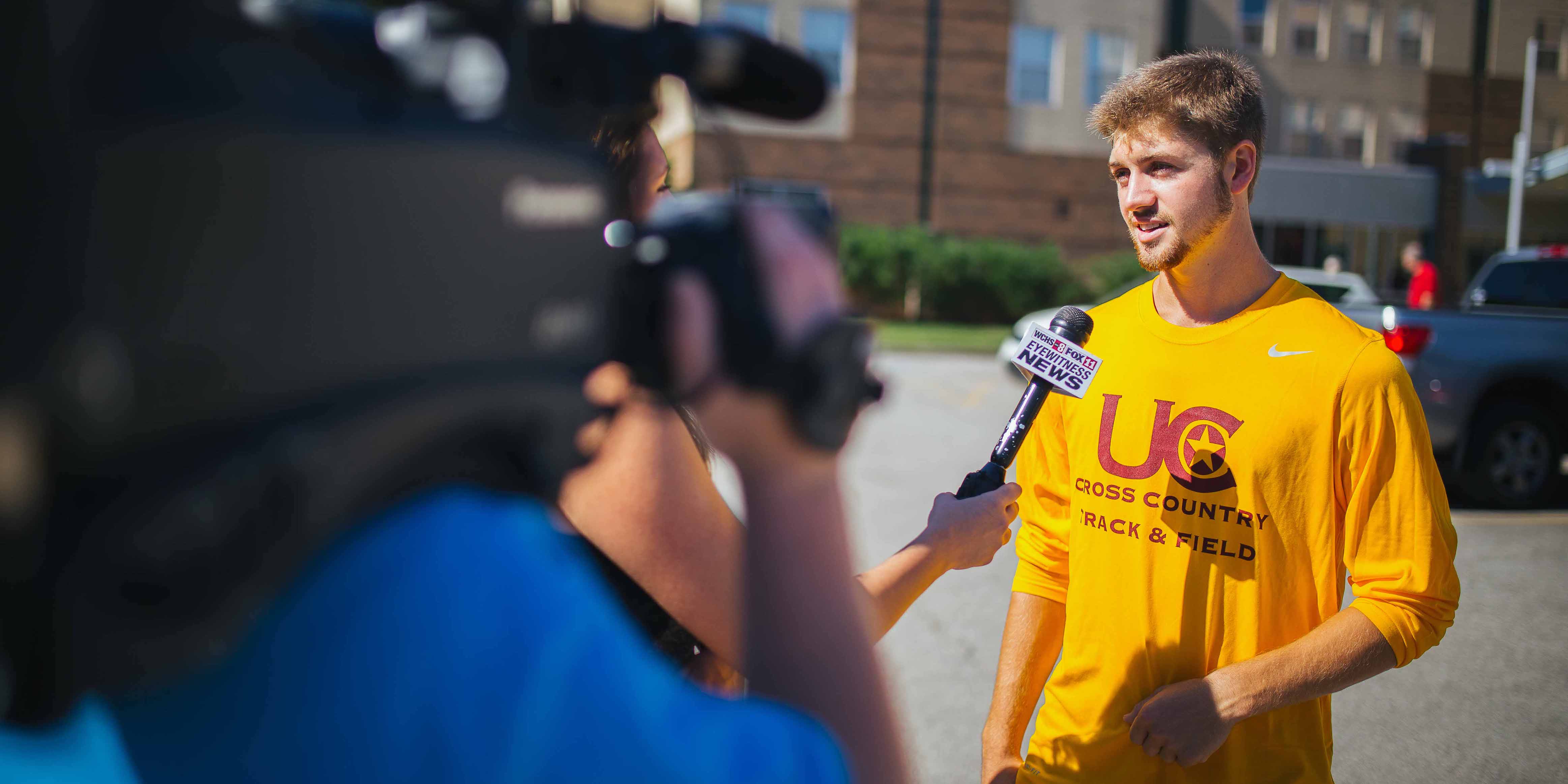 male student athlete being interviewed by local news anchor