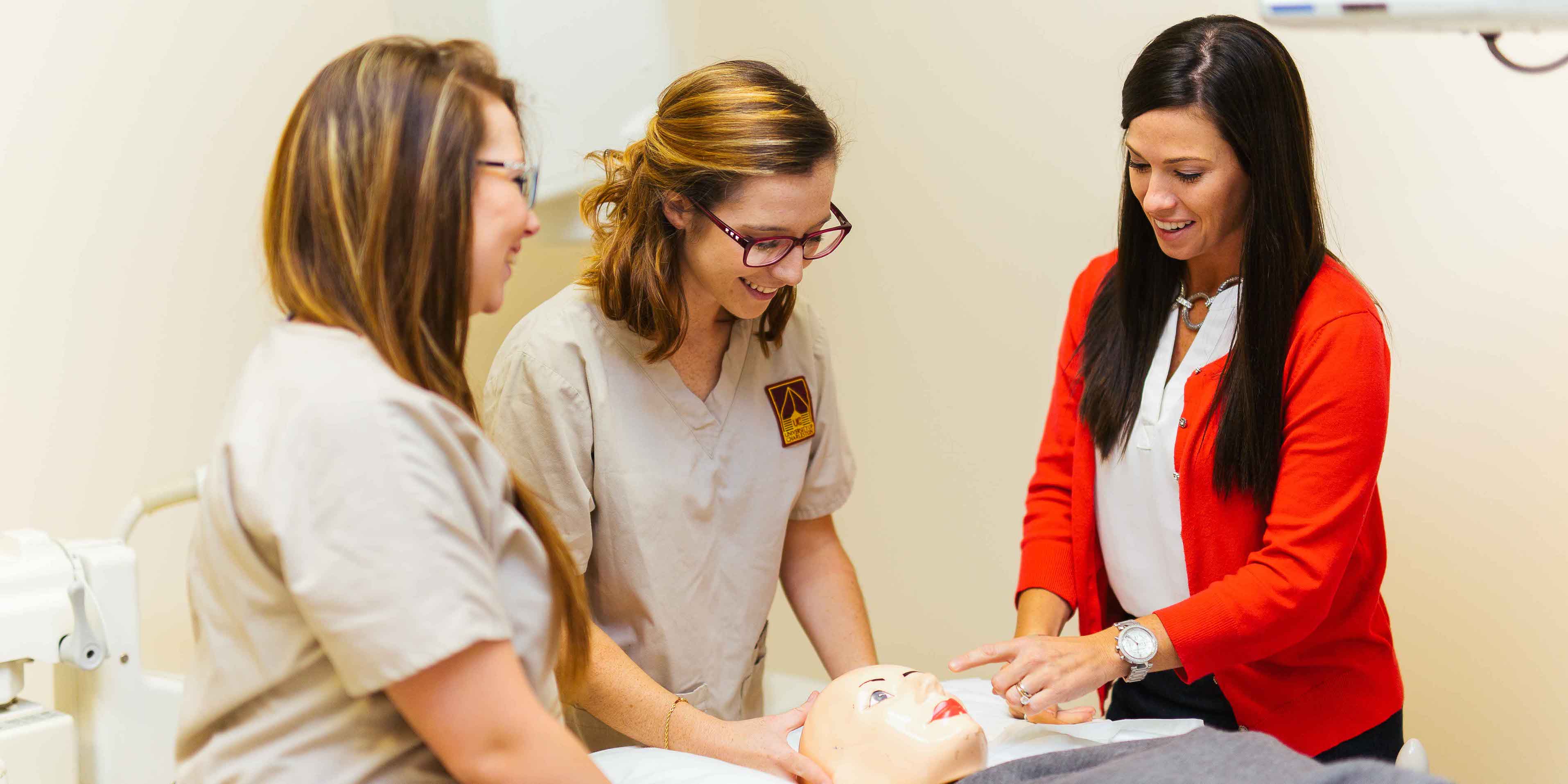 two female radiology students in scrubs being instructed by female professor