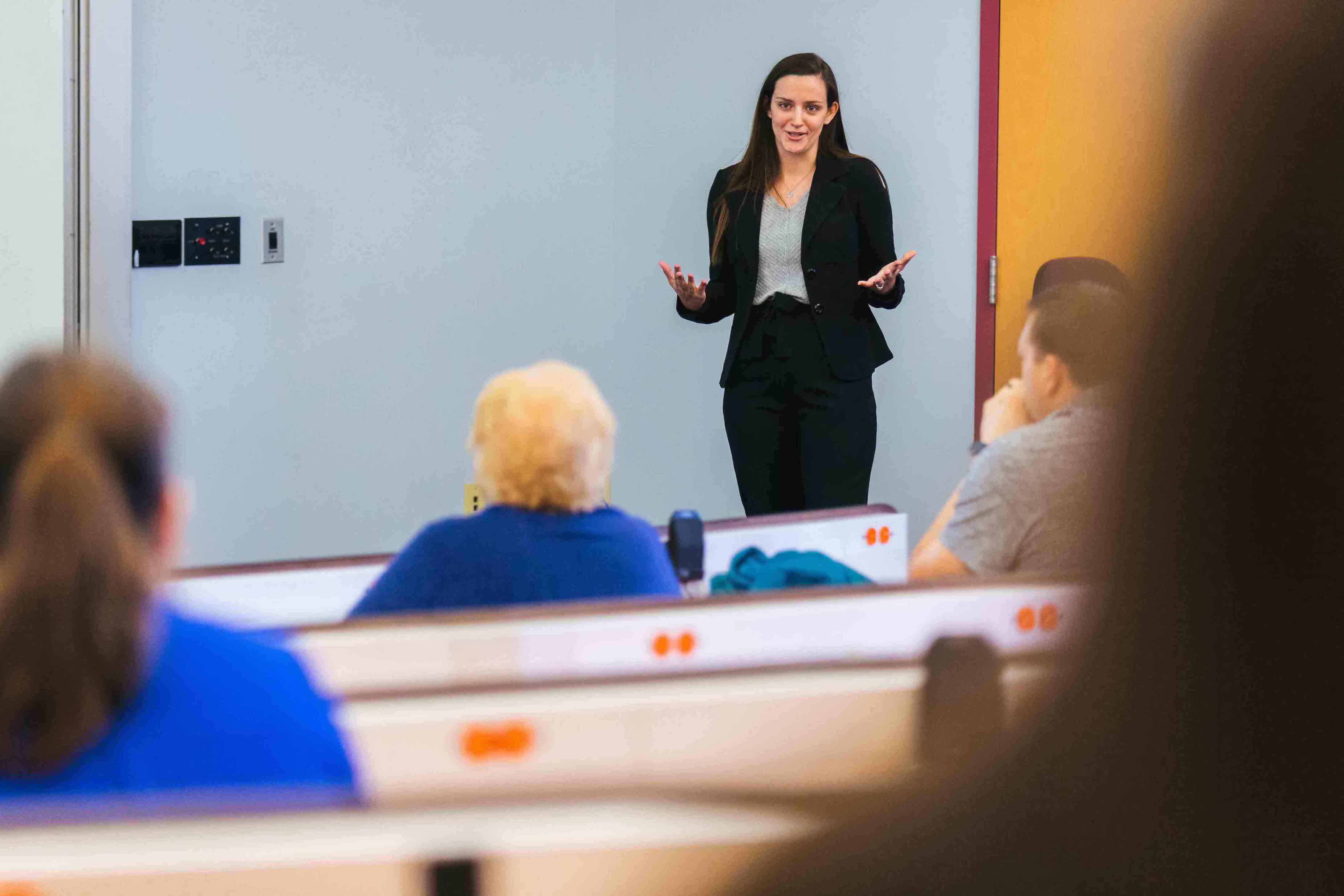 female student in business attire presenting in front of class