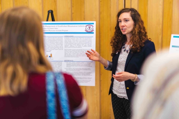 female physician assistant student discussing research poster at Innovation Showcase