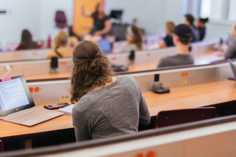 back view of female student taking notes during class lecture