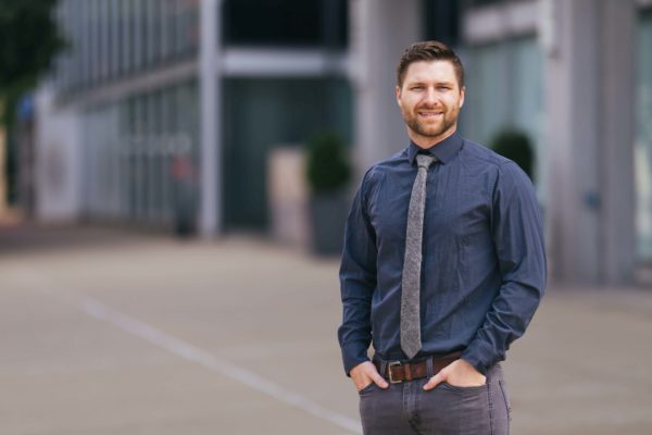 smiling male in front of a downtown building