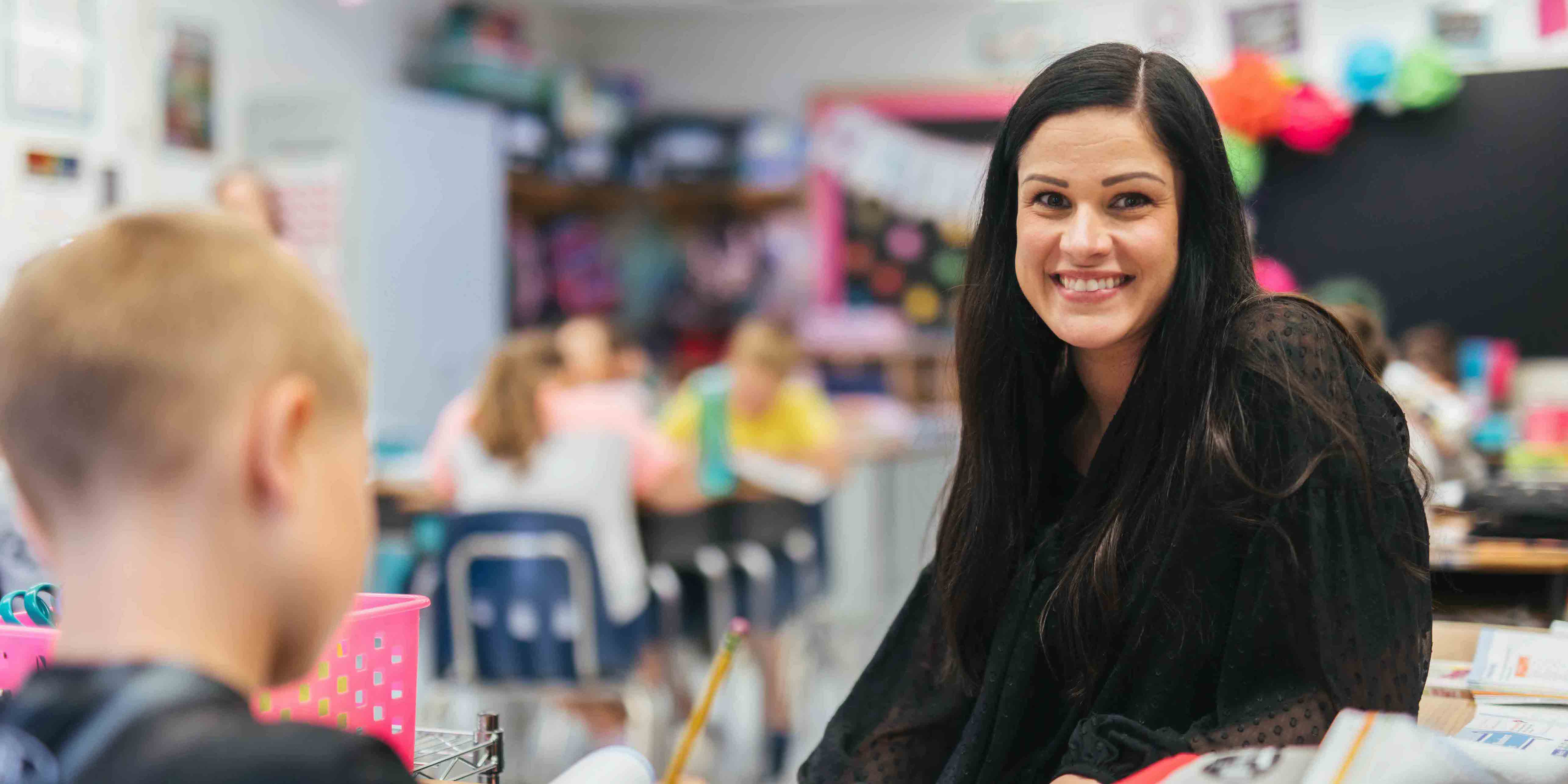 smiling female in elementary classroom with elementary students