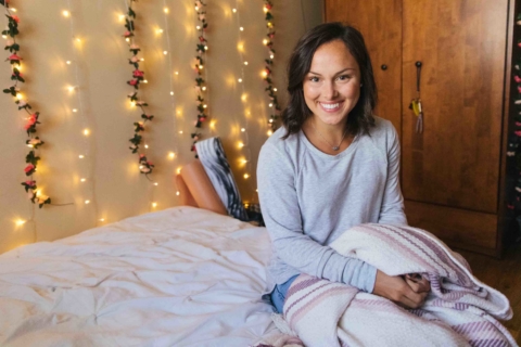 smiling female student sitting on her dorm room bed