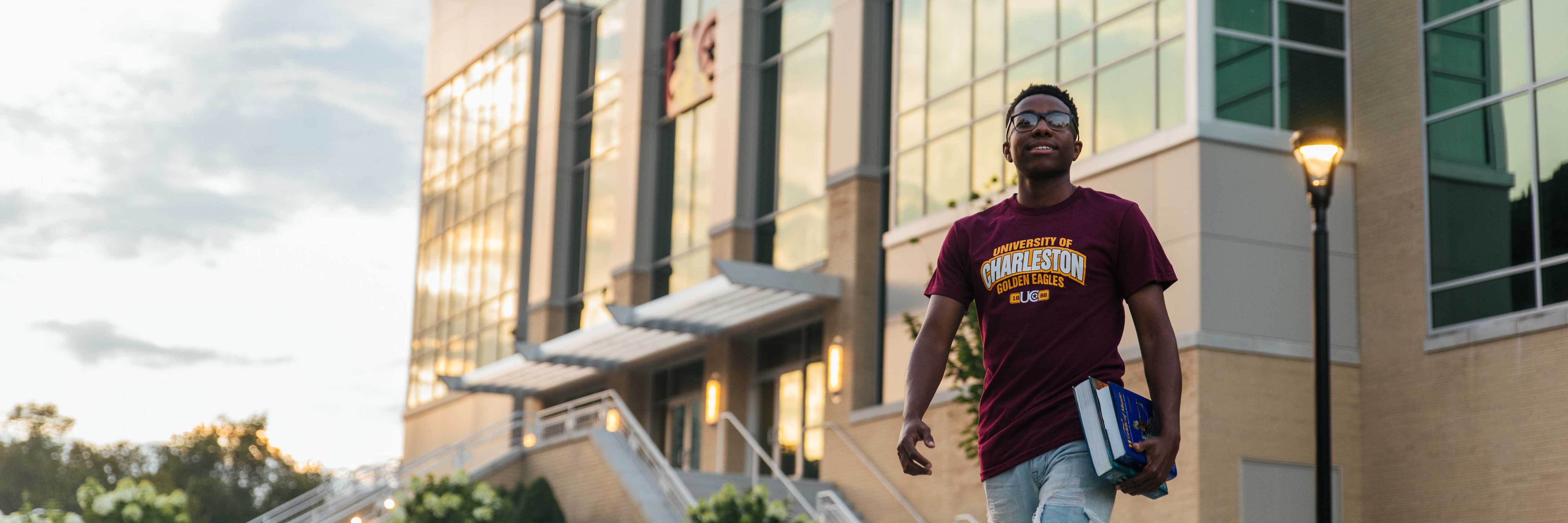 Male with books walking in front of the Innovation Center