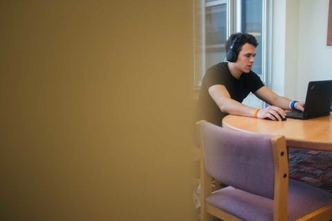Student wearing headphones in library while working on laptop