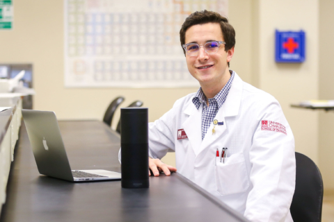 pharmacy student posing with computer and smart speaker