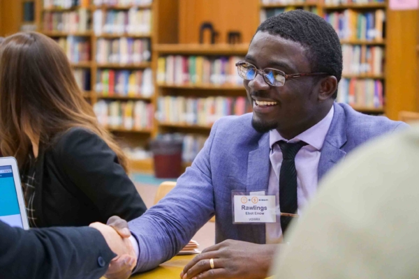 Male in professional attire shaking hands across a table