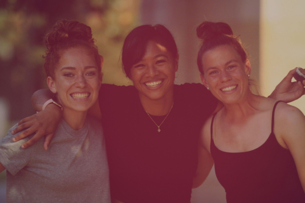 Three smiling females with arms locked and posing for photo