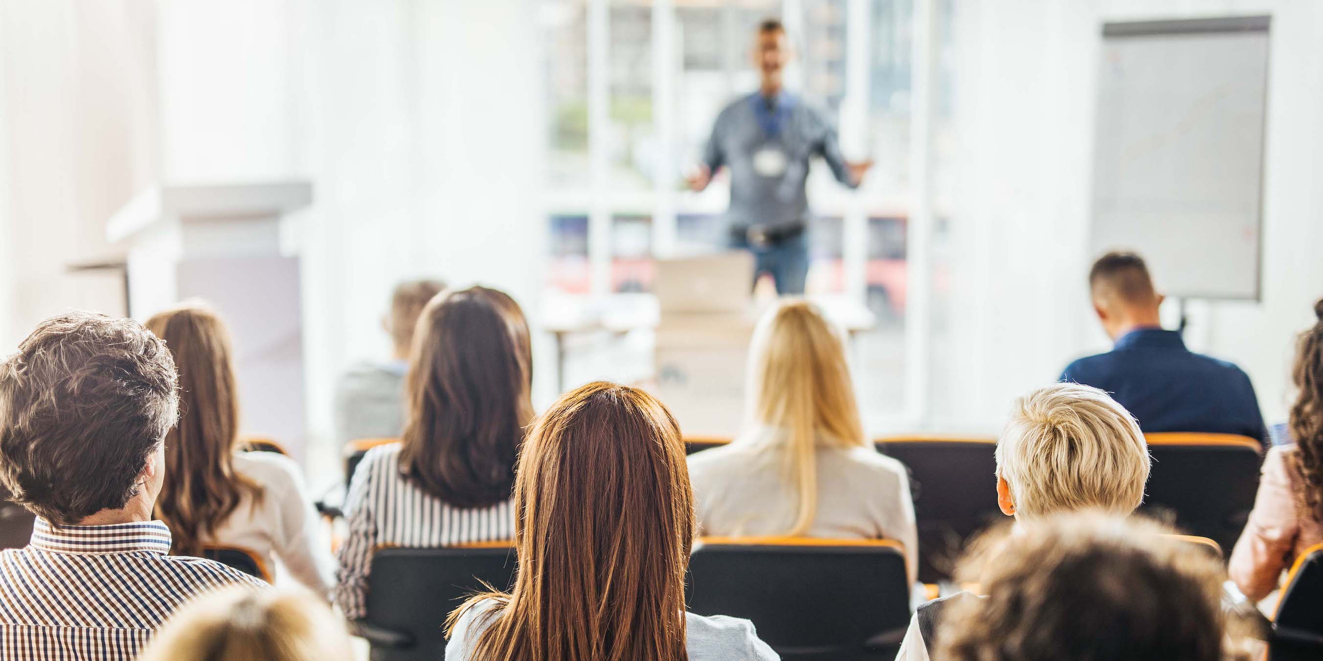 Back view of large group of business people having a training class in a board room.