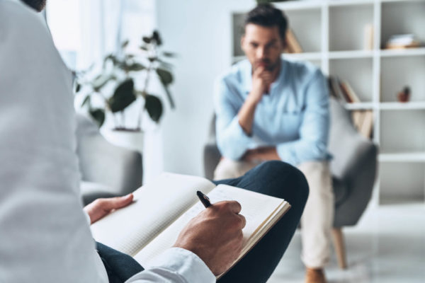man sitting in office across from person taking notes in book