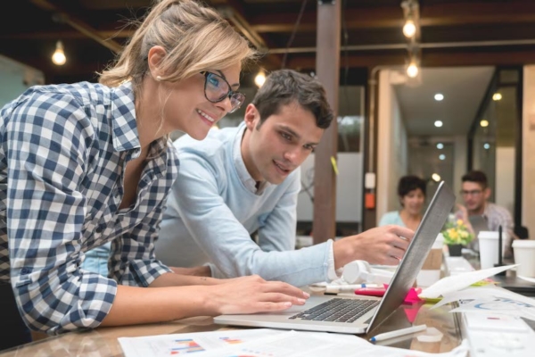 Group of people working online at a creative office using a laptop computer and smiling