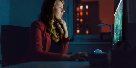 Side view of businesswoman working on a computer at night.