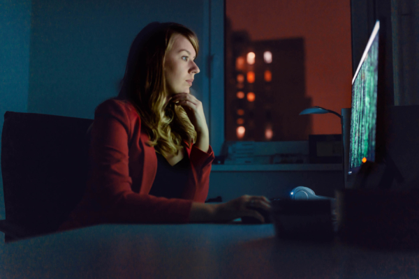 Side view of businesswoman working on a computer at night.