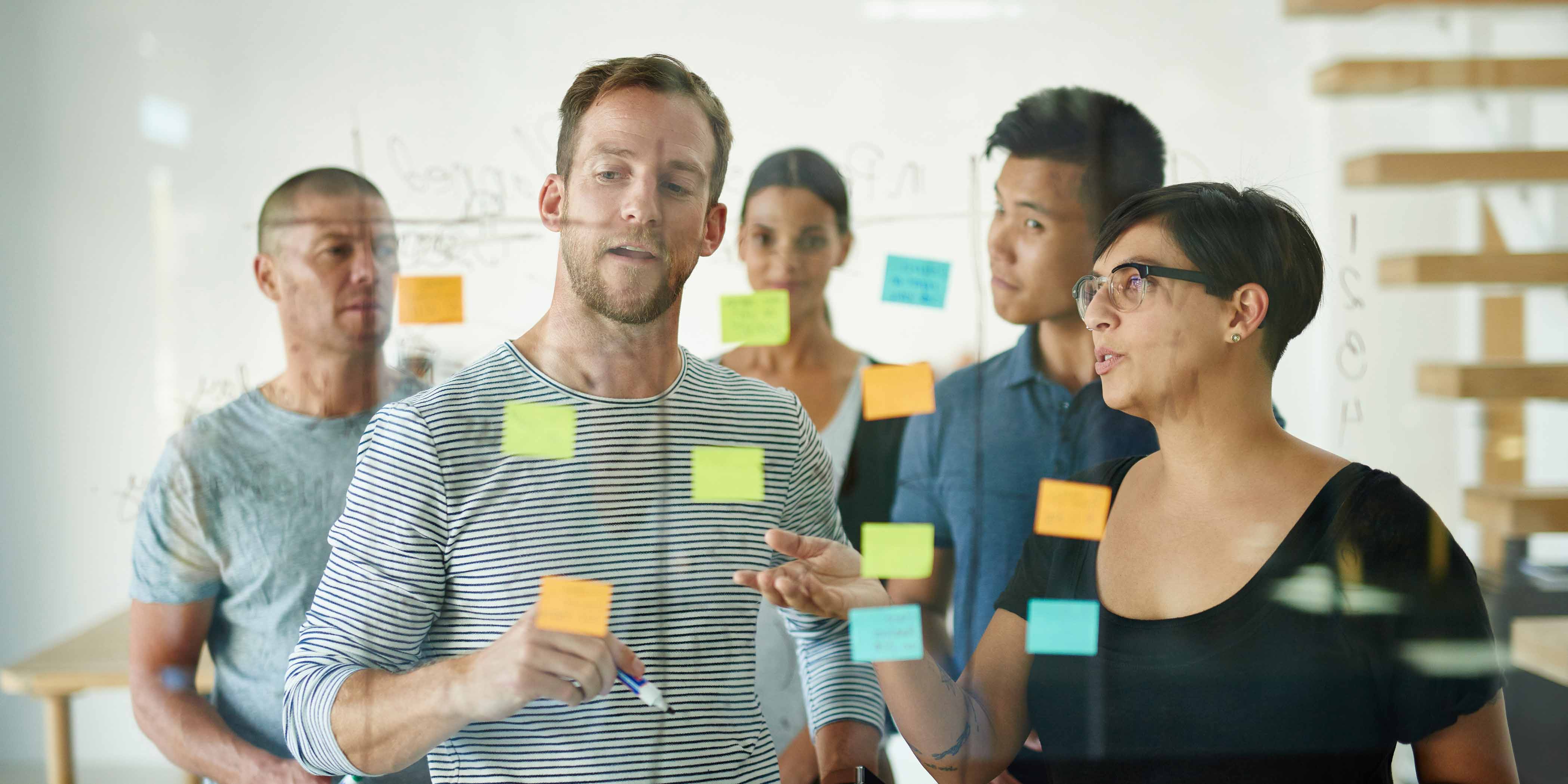 Group using sticky notes on a glass wall to generate ideas